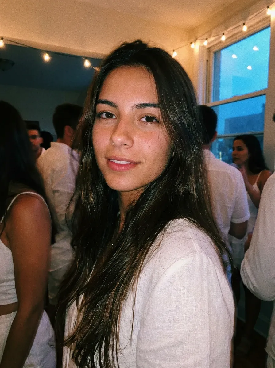 Original selfie input — woman with long dark hair in a white top indoors